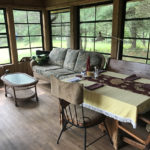 Dining table in screen porch folds out to accommodate 10
